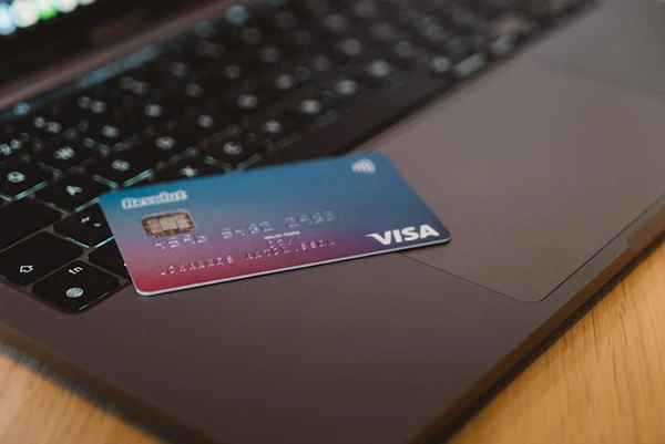 A customer's credit card is placed on a laptop to use with a payment portal.
